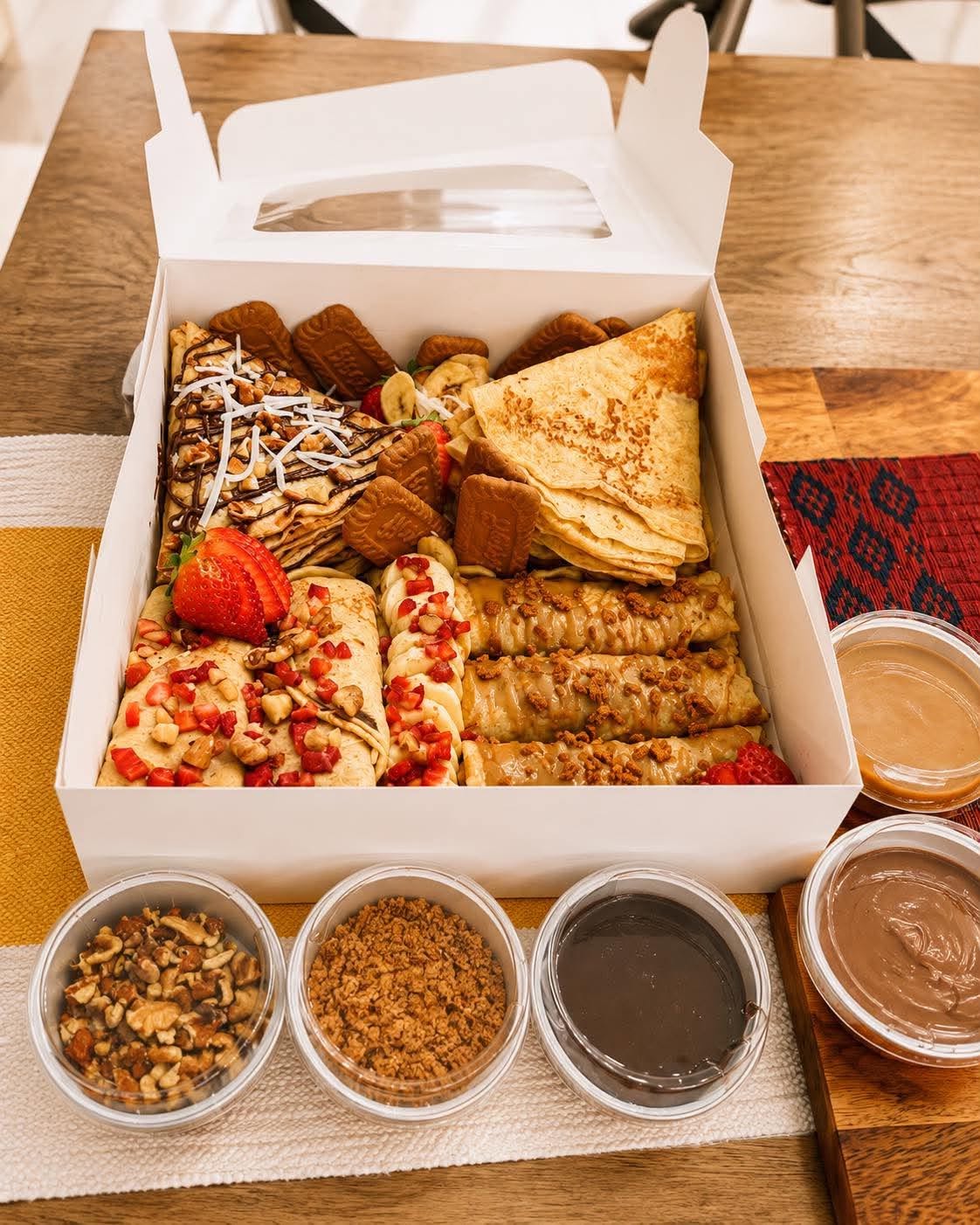 Open LOCO Crêpes box served with Nutella, caramel, berry sauce, nuts, and Biscoff crumbs